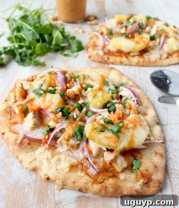 A perfectly baked and garnished Thai Peanut Chicken Naan Pizza, showcasing its vibrant colors and delicious toppings.