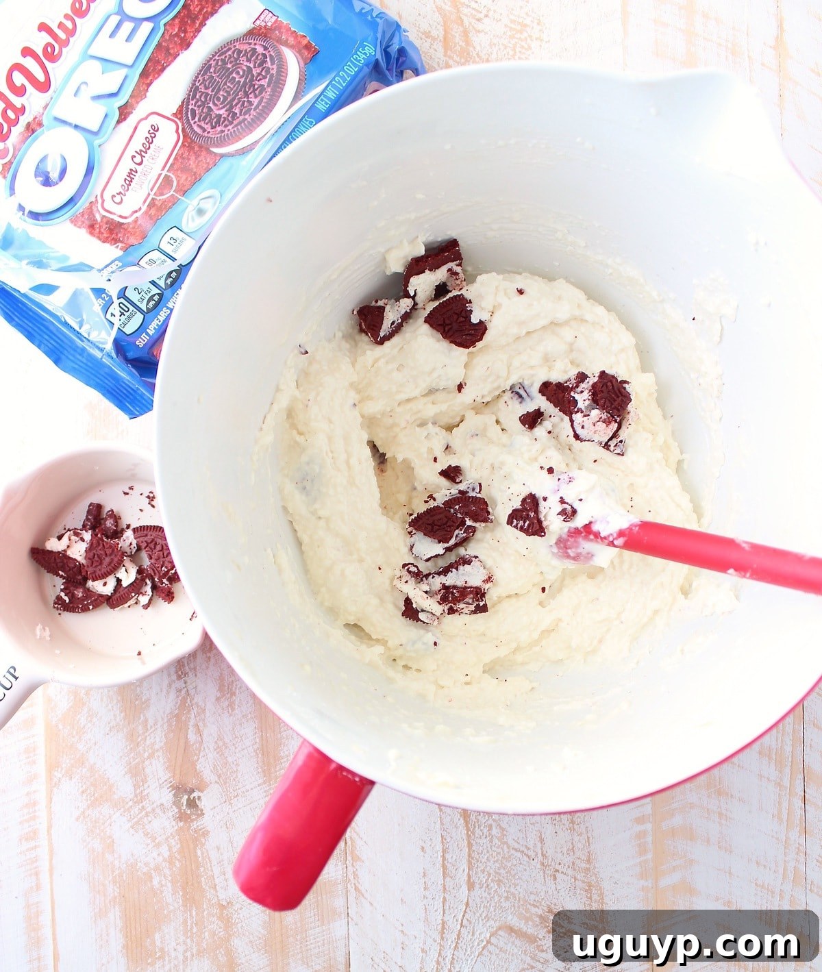 Creamy cheesecake filling infused with pieces of Red Velvet Oreos, ready to be spread over the prepared crust.
