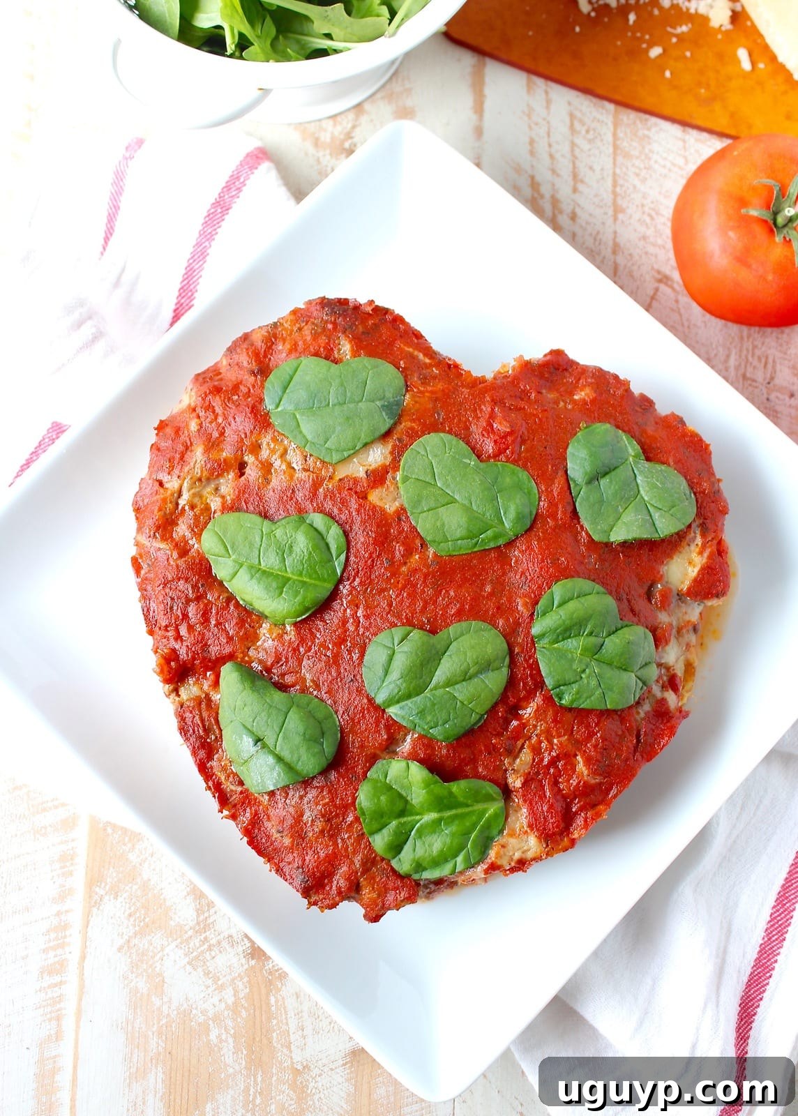 Heart-shaped Italian Meatloaf garnished with fresh spinach and small mozzarella hearts, adding an extra festive touch.