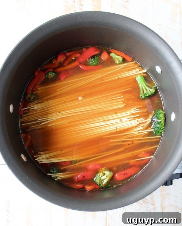 vegetables and noodles covered in broth in a large pot