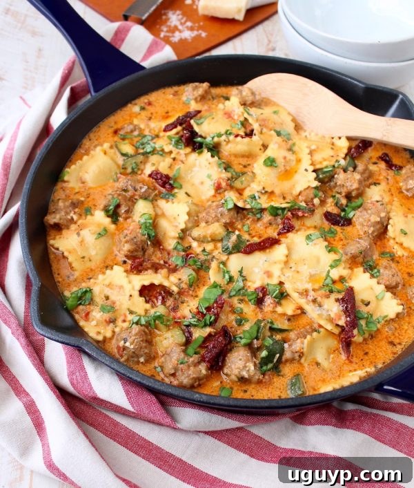 Close-up of freshly cooked One Pot Ravioli with creamy pesto sauce, Italian sausage, and sun-dried tomatoes, garnished with basil.