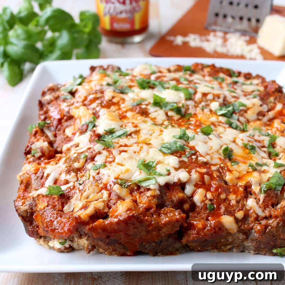 cooked meatloaf on plate topped with melted cheddar cheese and buffalo sauce 