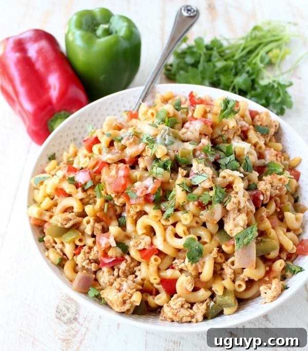 A close-up shot of a fork twirling creamy One Pot Chicken Fajita Pasta, emphasizing the texture and rich sauce.