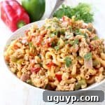 A vibrant close-up of One Pot Chicken Fajita Pasta, showcasing tender chicken, colorful bell peppers, and macaroni noodles coated in a rich, spicy sauce.