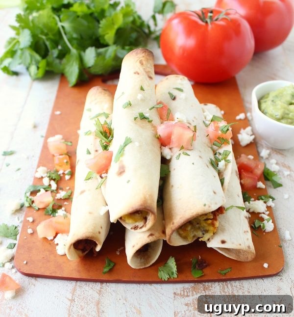 Breakfast Taquitos stacked on a white plate, garnished with fresh cilantro and a lime wedge, ready to be enjoyed.