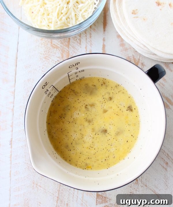 Raw eggs, milk, salt, and pepper whisked together in a bowl, ready to be scrambled.