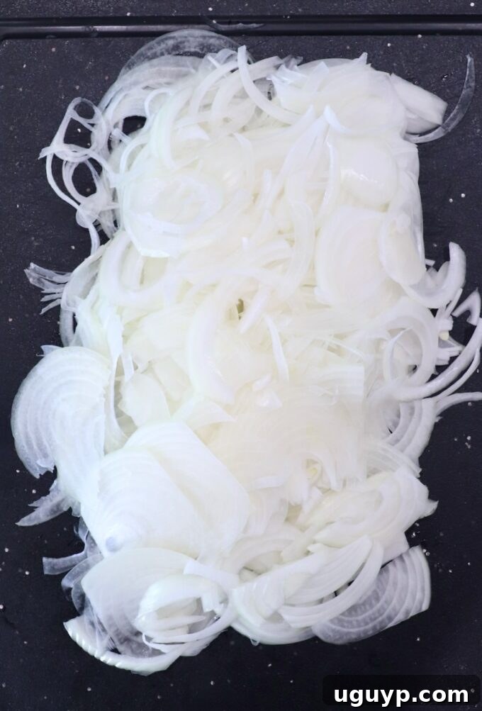 Thinly sliced onions prepared on a cutting board, ready for cooking.