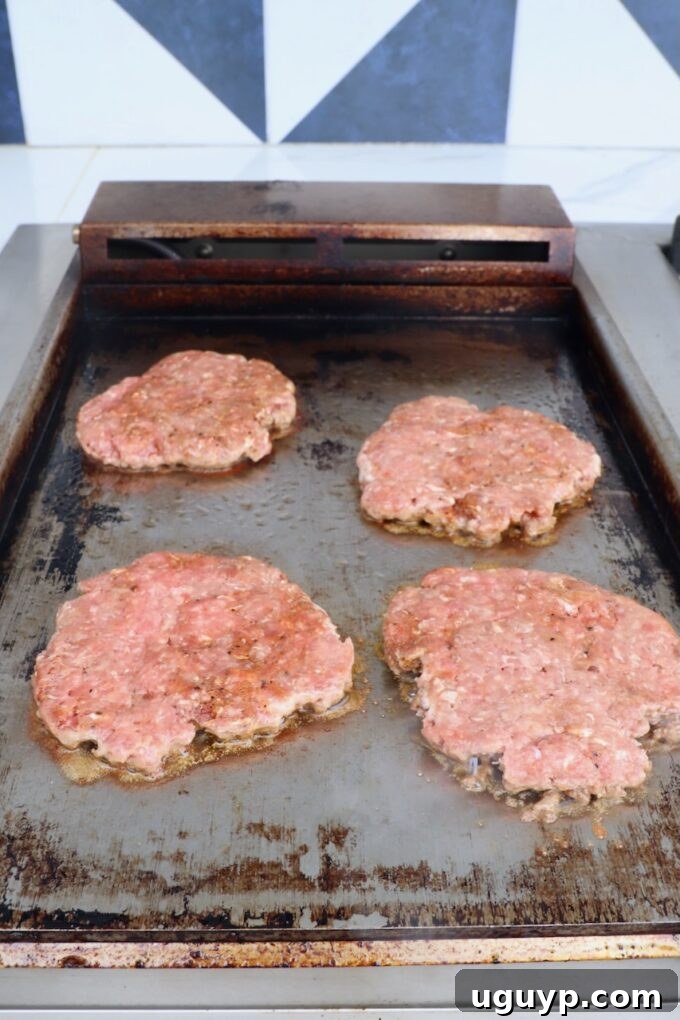 Smashed burger patties sizzling on the griddle, ready for the next step.