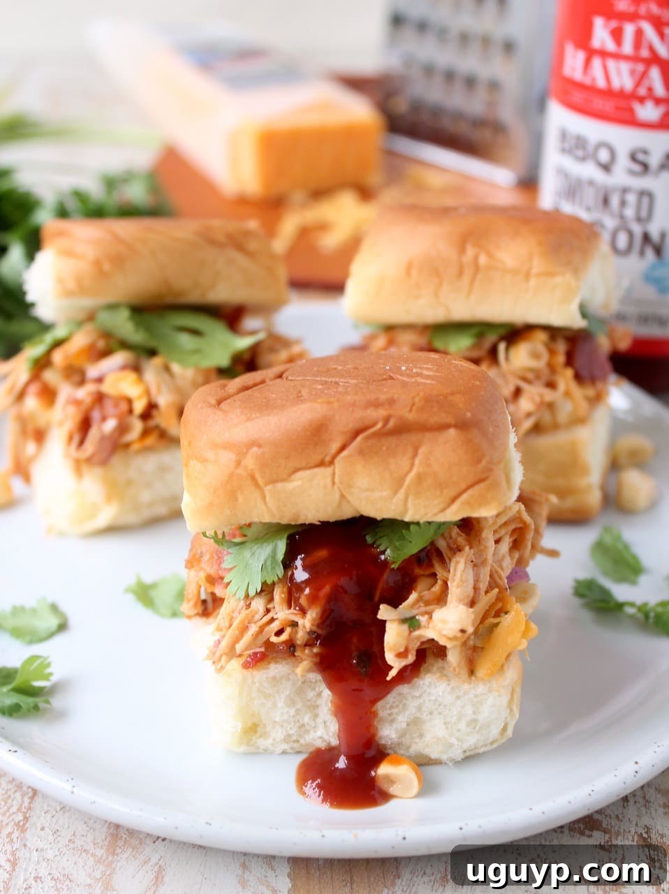 A plate full of BBQ Chicken Salad Sliders with a bowl of extra BBQ sauce for dipping or drizzling.