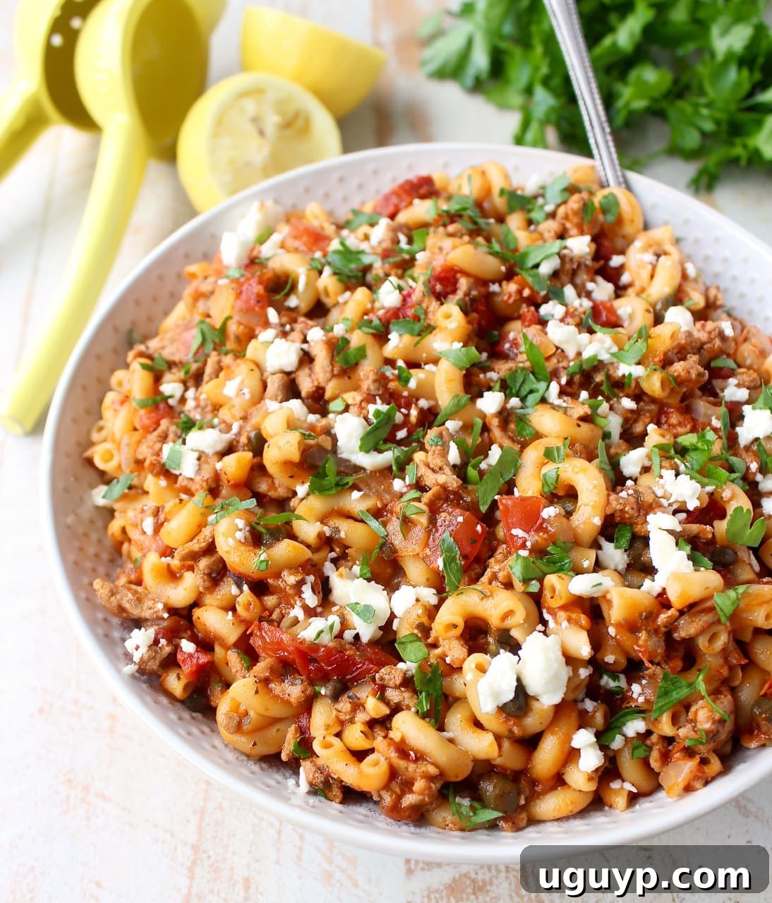 Delicious cooked one pot Greek pasta with ground turkey, diced tomatoes, and crumbled feta cheese in a white bowl, ready to serve.