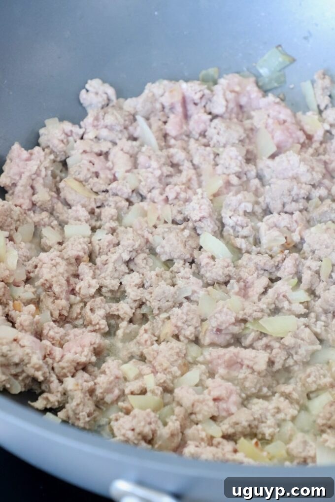 Sautéing diced onions with ground turkey in a large skillet, cooking until the meat is browned and the onions are tender.