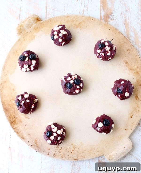 The vibrant red cookie dough being mixed in a bowl, showcasing the rich color before adding chocolate chips or blueberries.