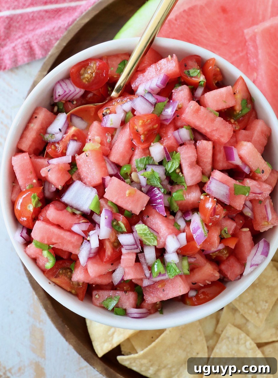 A large bowl of freshly prepared watermelon salsa, with a serving spoon resting inside, ready for a gathering.