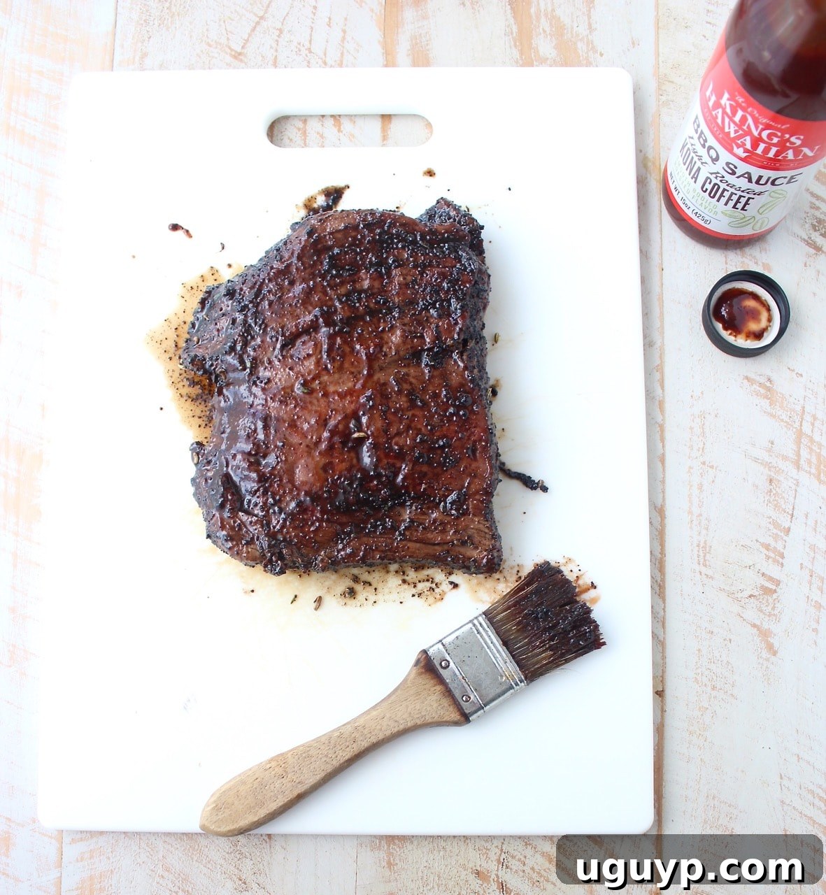 grilled steak covered with bbq sauce on cutting board with pastry brush