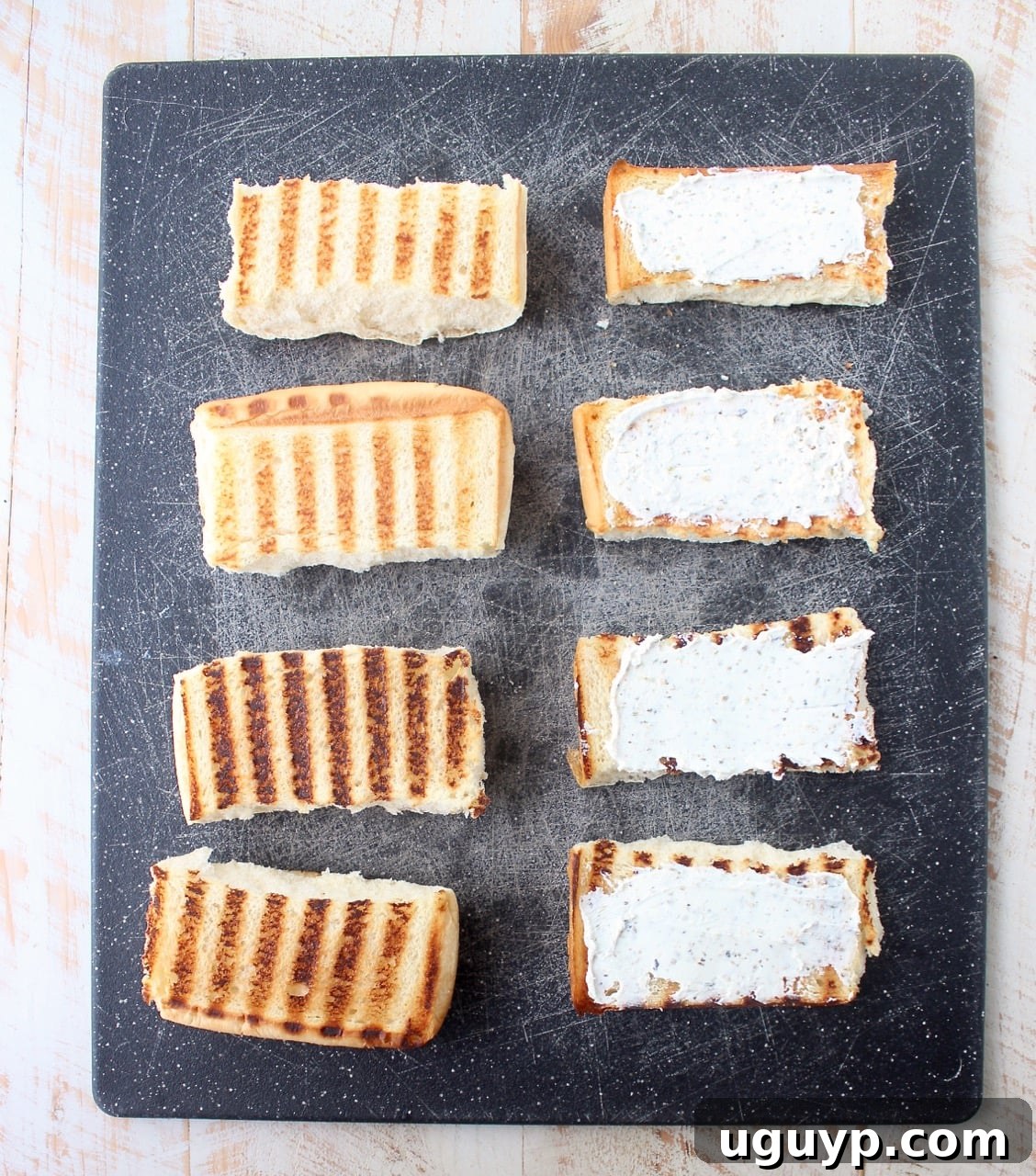 grilled sub rolls on cutting board, half of the rolls topped with herbed goat cheese