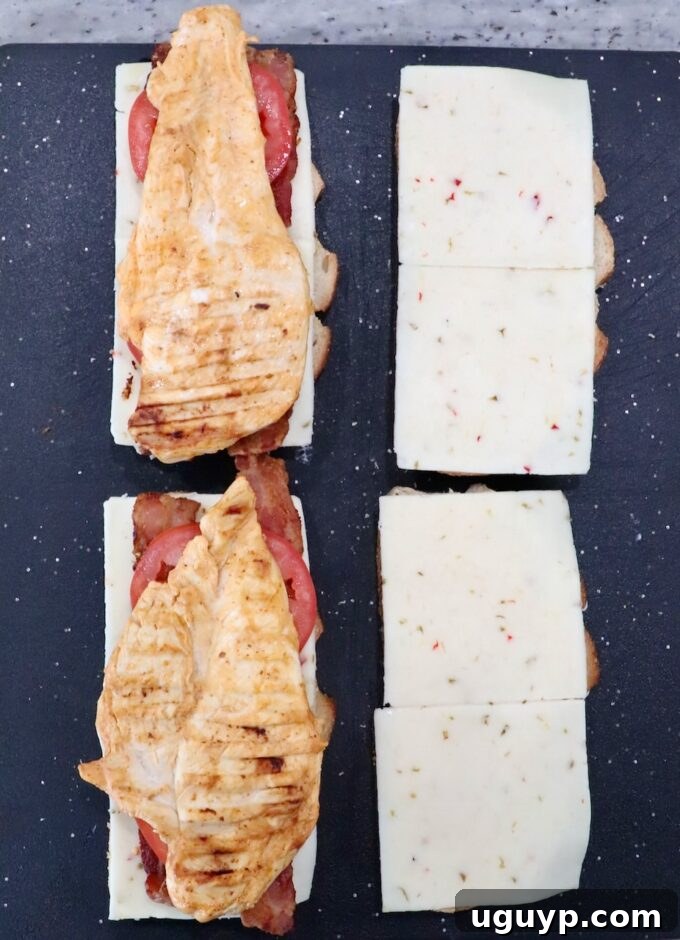 bread topped with slices of pepper jack cheese and grilled chicken on cutting board