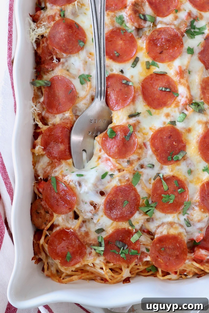 Delicious Pizza Baked Spaghetti in a casserole dish with a large serving fork, ready to be enjoyed.