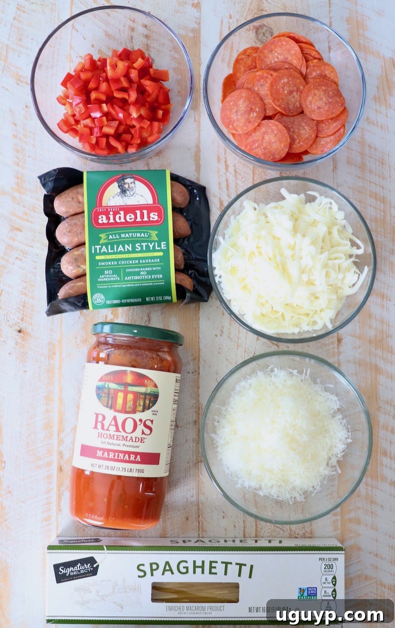 Ingredients for pizza baked spaghetti laid out on a white wooden board.
