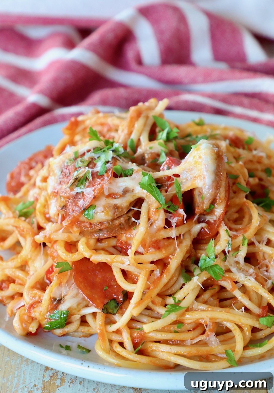 A serving of pizza baked spaghetti on a white plate, garnished with fresh herbs.