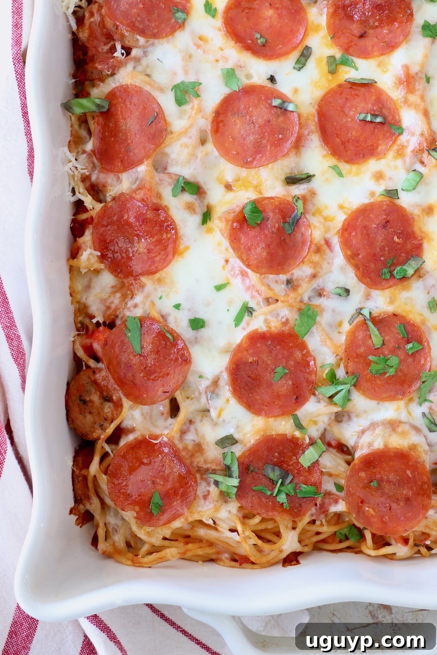 Close-up of baked spaghetti in a casserole dish topped with melted cheese and pepperonis, showing the delicious texture.