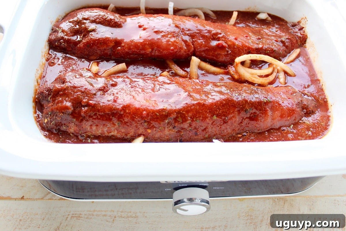 Two pork tenderloins in a slow cooker, fully covered with the Dr Pepper BBQ sauce mixture.