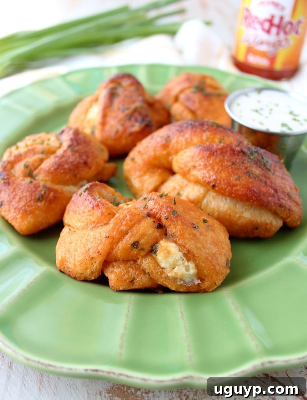 Freshly baked Buffalo Cheesy Garlic Knots, hot from the oven and glistening with buffalo sauce.