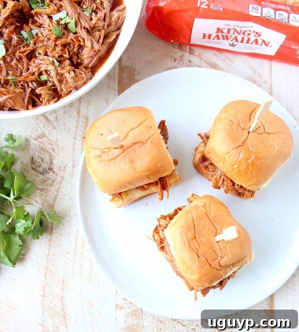 Delicious Hawaiian Chicken Sliders with shredded chicken, pineapple, and BBQ sauce on King's Hawaiian rolls, ready to serve.
