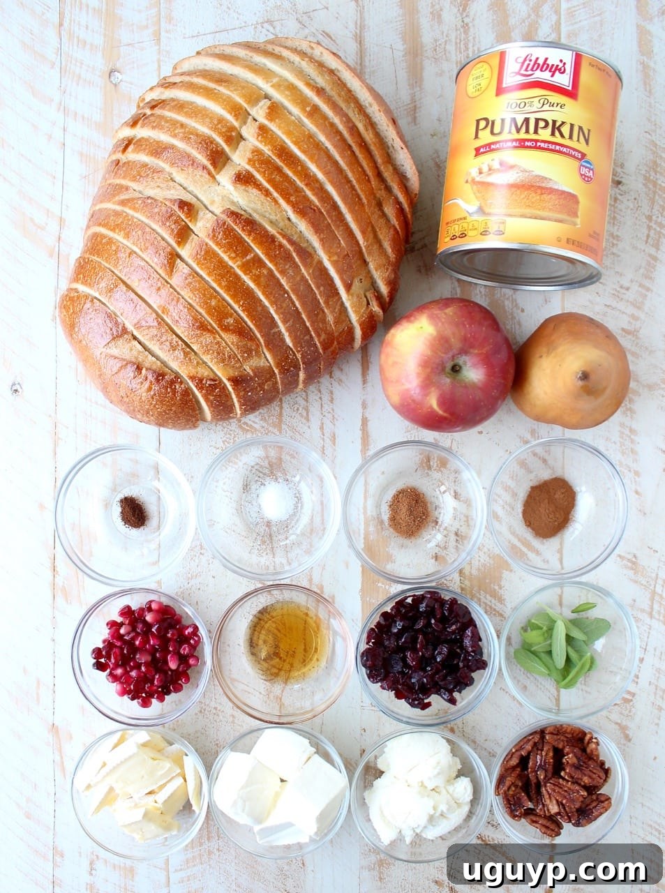 A display of pumpkin toast ingredients and various toppings laid out artfully on a white wooden board.