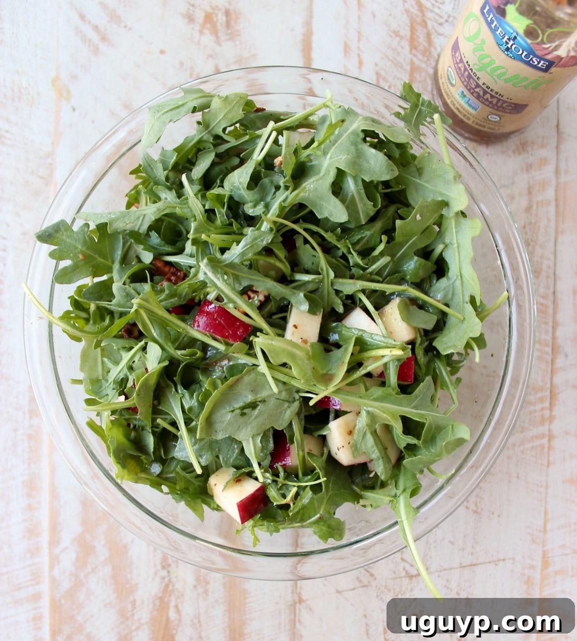 arugula salad with diced apples in a glass bowl