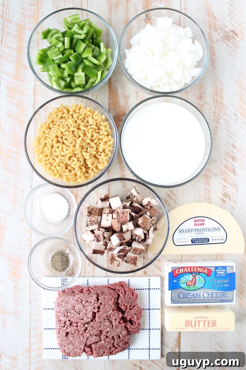 ingredients for Philly cheesesteak mac and cheese on white wood board