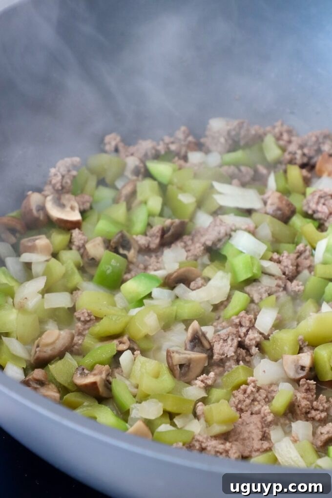 cooked bell peppers, onions and ground beef in skillet