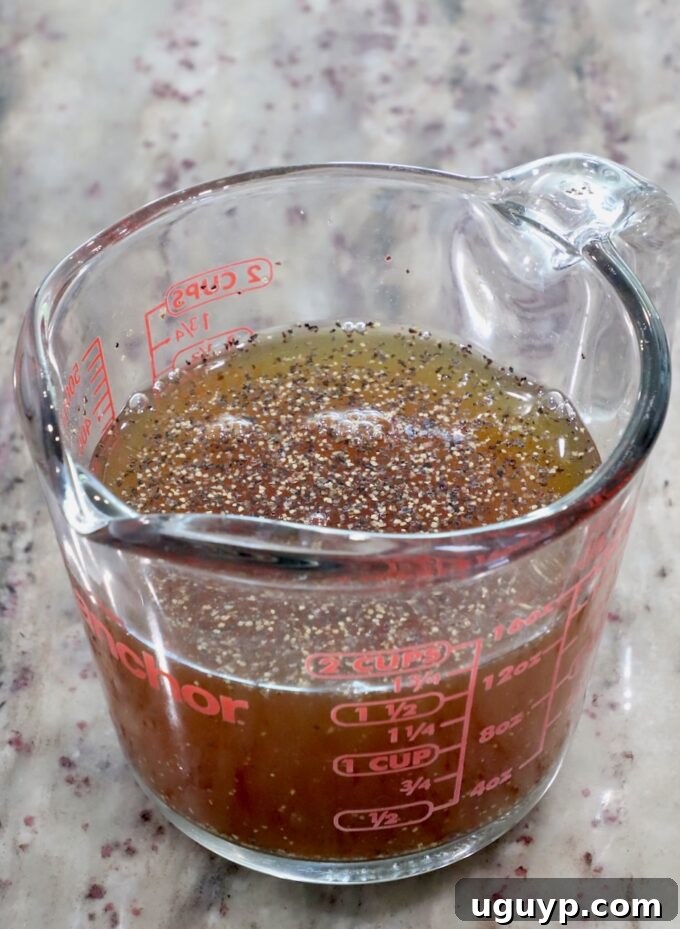 Maple syrup and apple cider combined in a glass measuring cup with salt and pepper