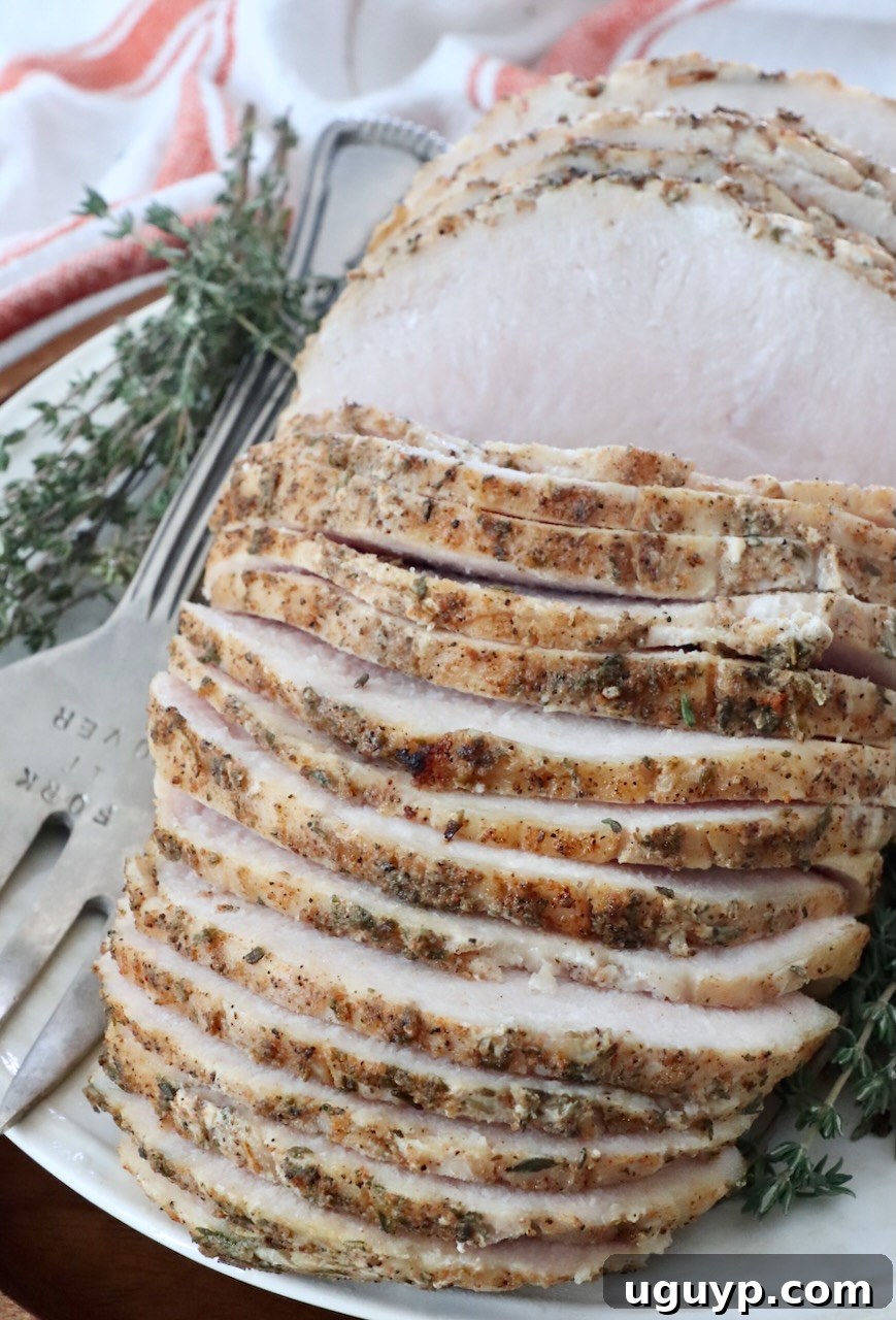 Sliced sous vide turkey breast on a serving platter, garnished with fresh thyme sprigs and ready to enjoy.