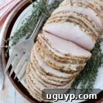 sliced turkey breast on a plate with fresh thyme and a serving fork