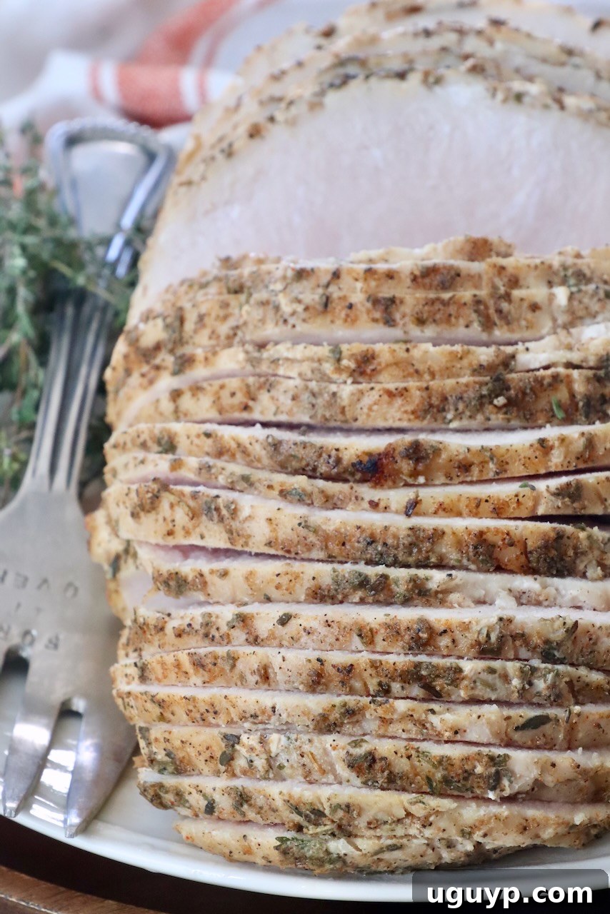 Perfectly sliced sous vide turkey breast on a plate with a large serving fork, showcasing its juicy interior.