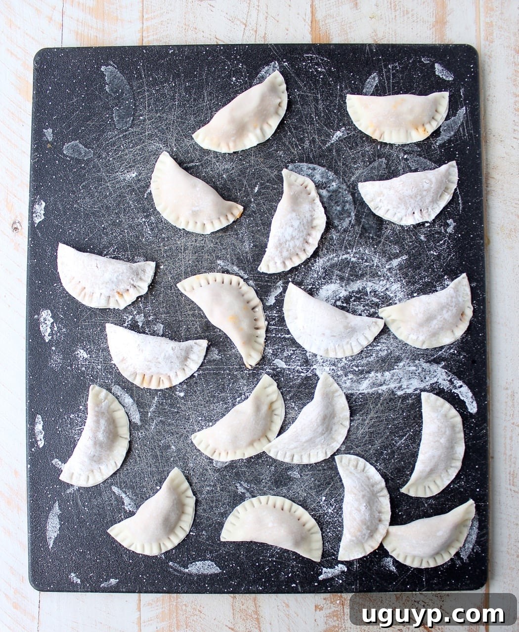 A wonton wrapper filled with mashed potatoes being folded and sealed, showing the formation of a pierogi