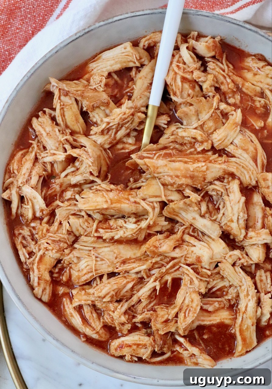Shredded chicken generously coated in rich buffalo sauce, presented in a bowl with a fork, ready to be enjoyed.