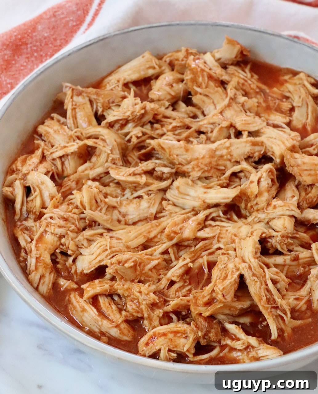 A close-up shot of perfectly shredded buffalo chicken in a rustic bowl, ready for serving.