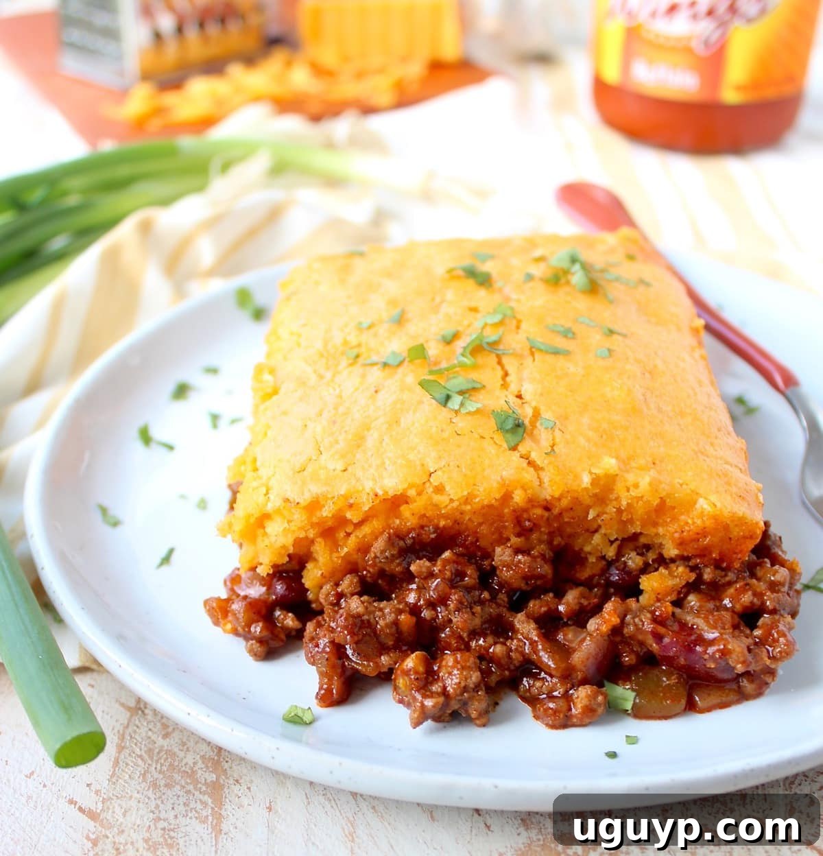 A perfectly portioned piece of Buffalo Cheddar Cornbread Chili Pie, showcasing its vibrant layers, sitting on a clean white plate.