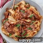Instant Pot Beef Ragu sauce tossed with pasta noodles in a bowl with a fork