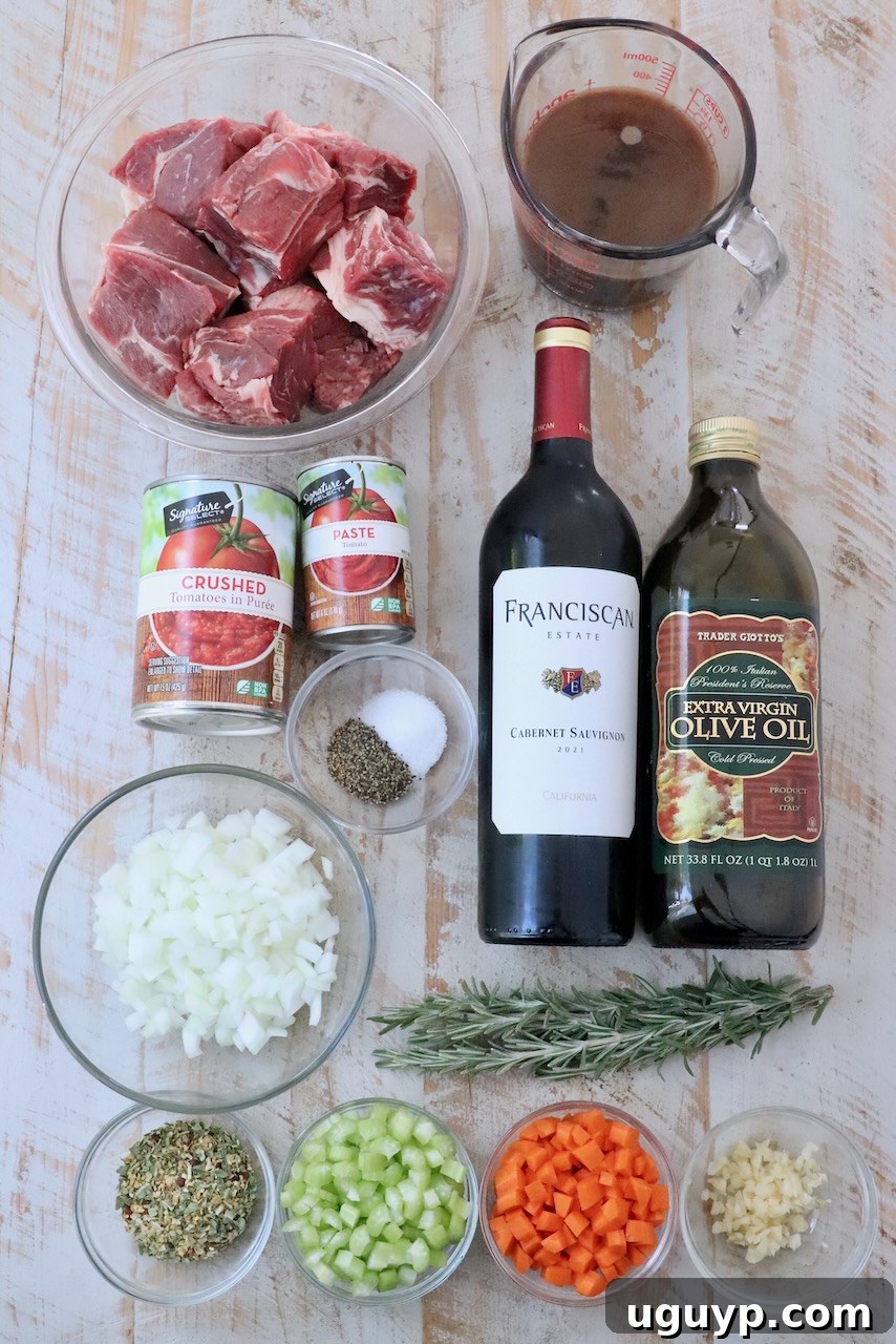 A selection of fresh ingredients laid out on a white wooden board, including beef chuck roast, vegetables, herbs, and canned goods, ready for making Instant Pot Beef Ragu.