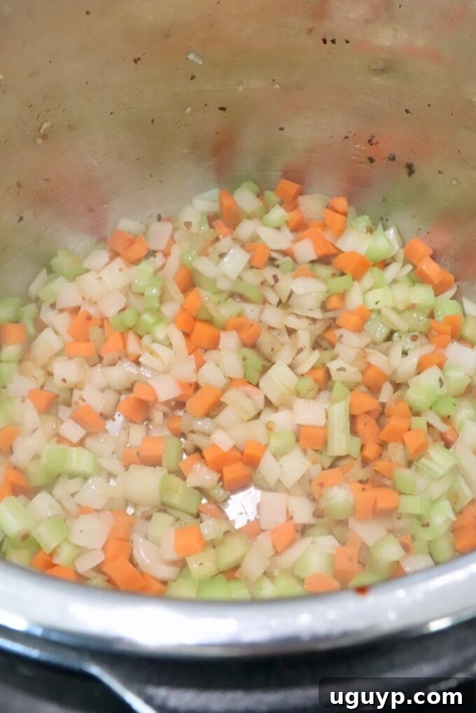 Diced onions, carrots, and celery sautéing in the Instant Pot, forming the aromatic base for the ragu.
