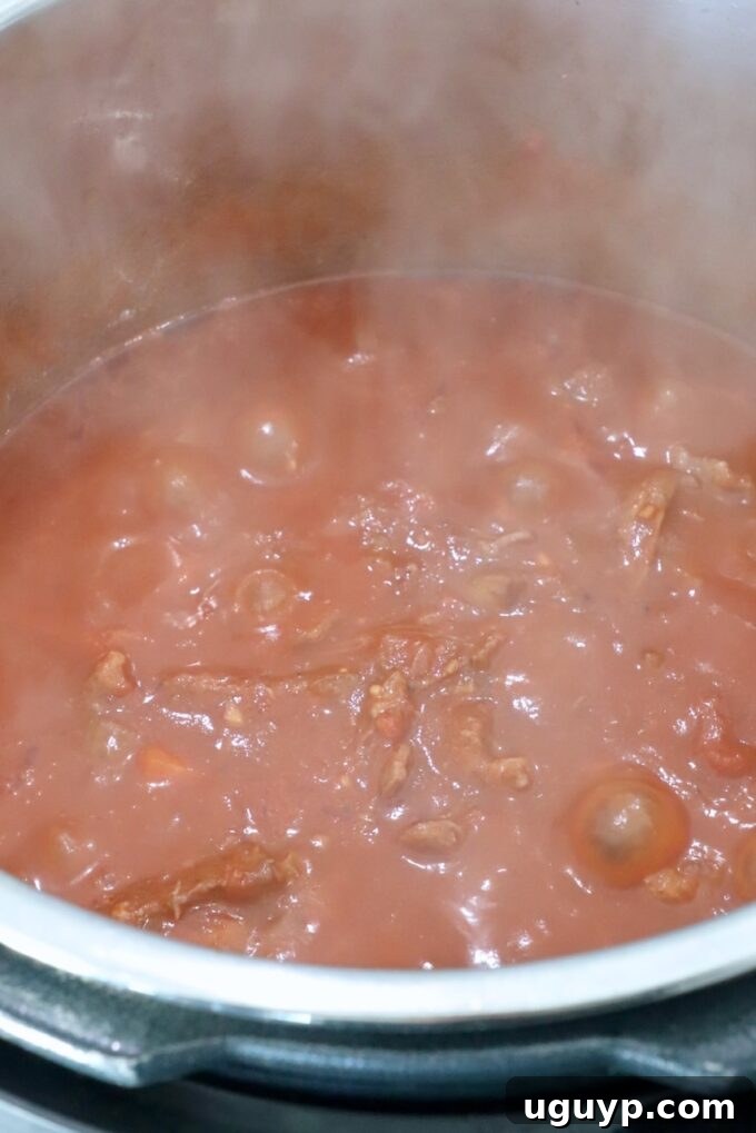 Shredded beef fully incorporated into the thick ragu sauce in the Instant Pot, ready to be served.
