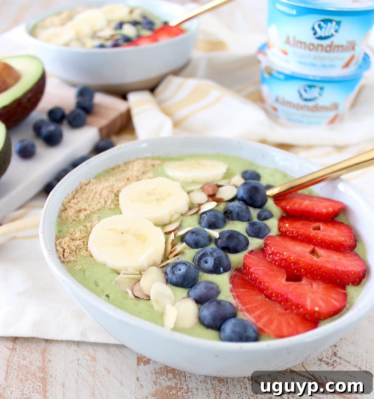 A top-down view of a generously sized avocado smoothie bowl, beautifully arranged with colorful toppings like fresh strawberries, blueberries, kiwi slices, and a sprinkle of seeds, ready to be enjoyed.