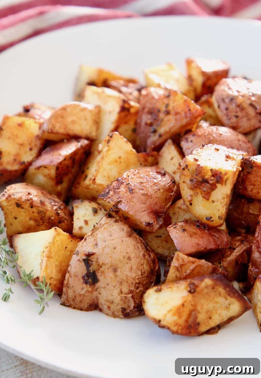 Crispy Roasted Garlic Cajun Potatoes on a white plate, garnished with fresh herbs