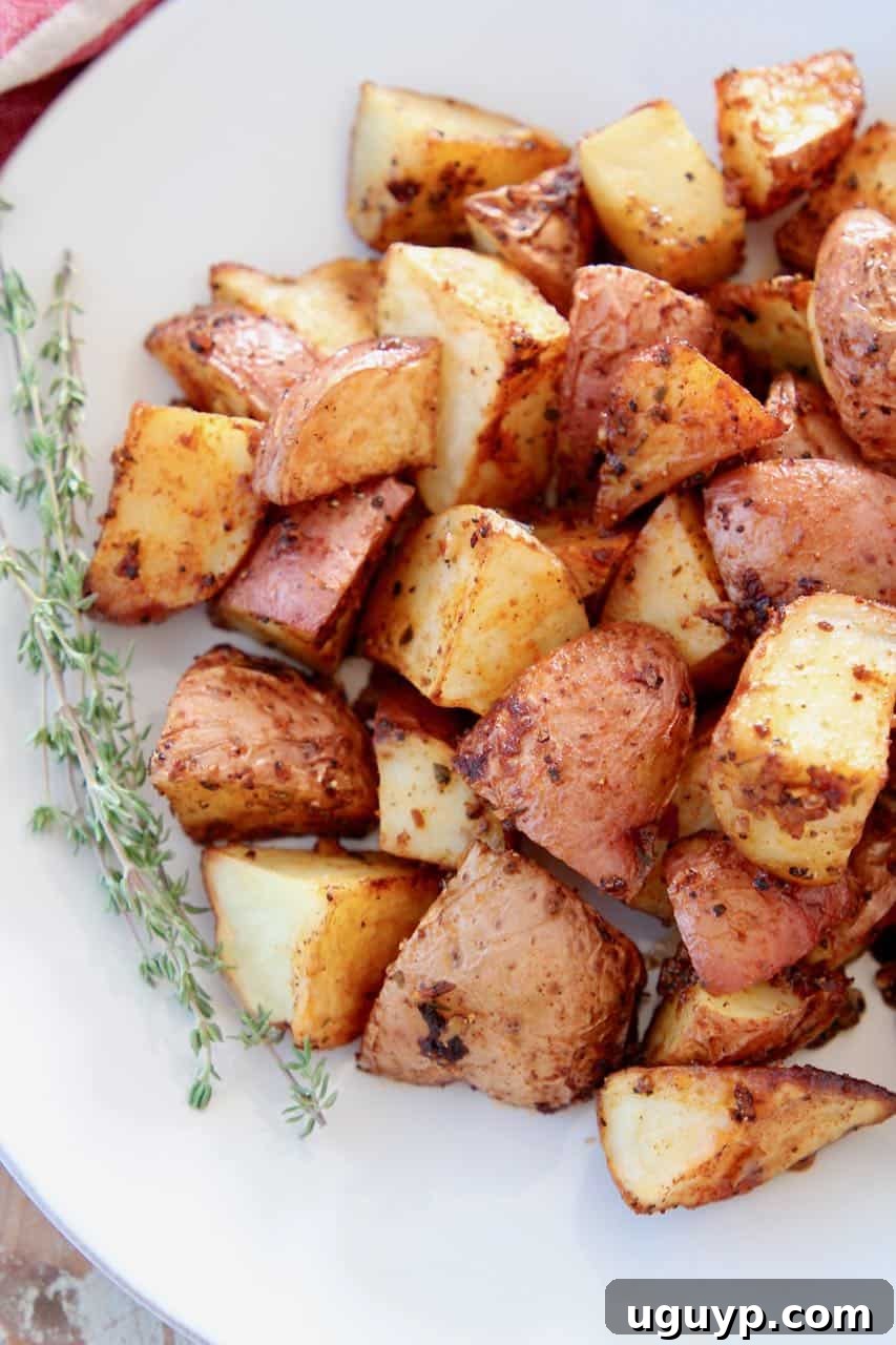 Overhead shot of crispy roasted red Cajun potatoes on a plate with fresh thyme sprigs, ready to serve