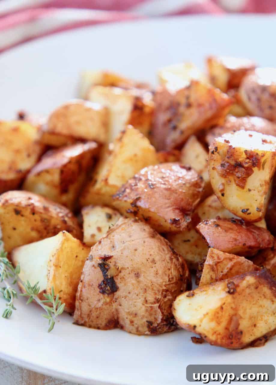 Close-up of golden brown oven roasted cubed Cajun potatoes on a white plate