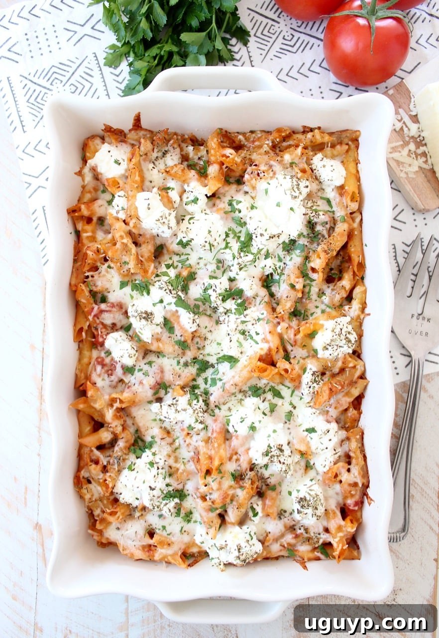 Golden-brown baked ziti, bubbling with melted cheese in a ceramic casserole dish, ready to be served for a comforting family meal.