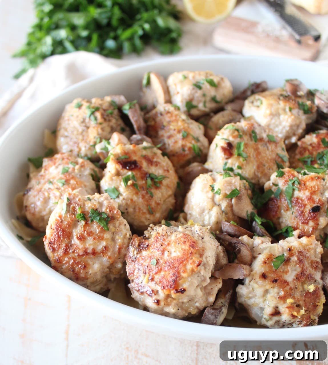 Delicious chicken and pork meatballs with sliced mushrooms in a creamy marsala sauce in a baking dish.