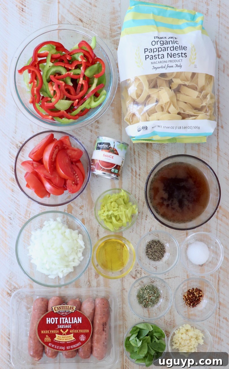 A collection of fresh ingredients laid out, including wide egg noodles, bell peppers, Italian sausage, fresh basil, garlic, and onions, ready for making Italian Drunken Noodles.